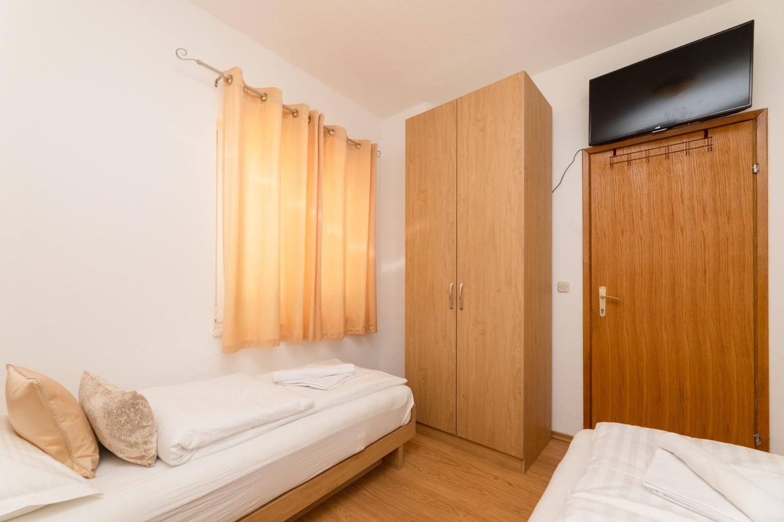 A small, single-room apartment with a bed, a wardrobe, and a television.