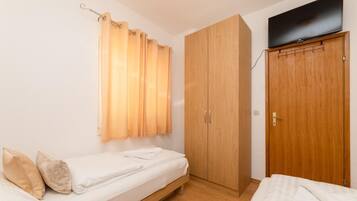 Un apartamento pequeño de una sola habitación, con cama, armario y televisión.