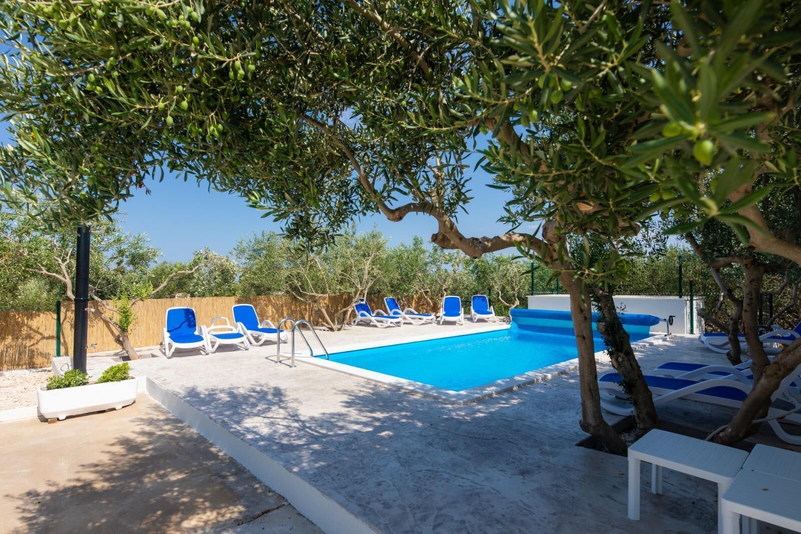 A poolside area with blue lounge chairs and a swimming pool.