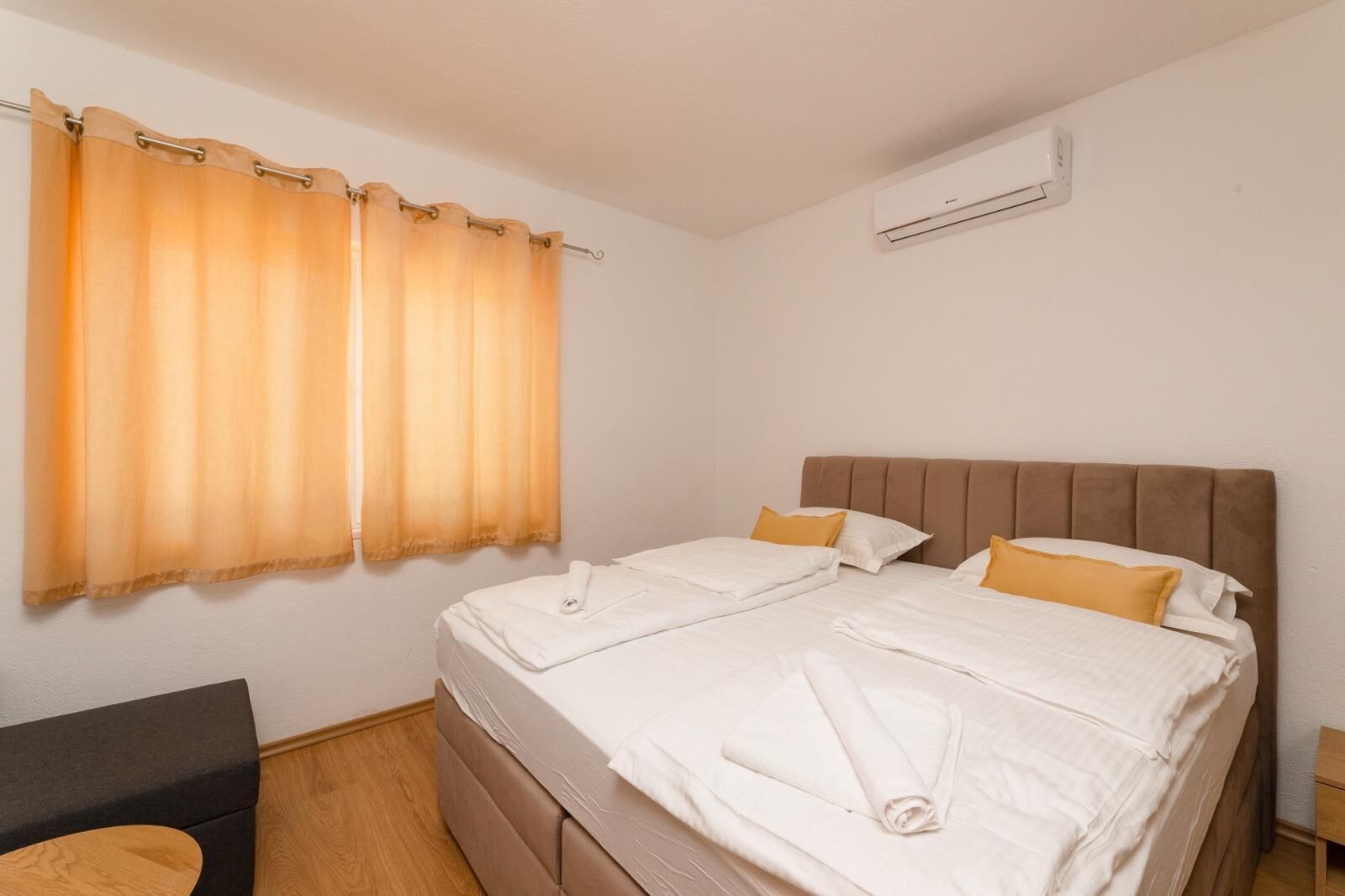 A double bed with white linens, two pillows, and a brown headboard.