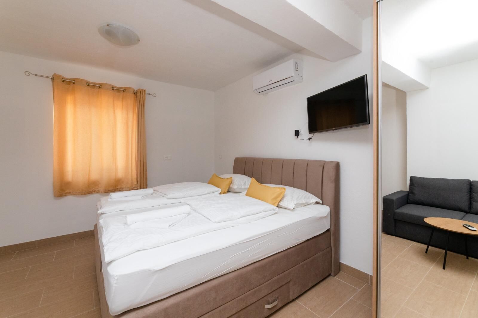 A hotel room with a bed, a TV mounted on the wall, and a sofa.
