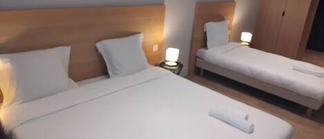 A hotel room with two single beds, each with a headboard, a nightstand, and a lamp. There is a wardrobe in the room.