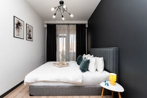 Quarto moderno com cama, mesa de cabeceira e obra de arte na parede.