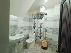 A bathroom with a toilet, sink, and a trash bin. - The Royal Green Residency (Varanasi)