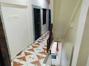 Um corredor com piso estampado, uma escada e uma porta com janela.