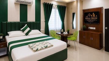 A hotel room with a bed, a desk, a chair, an air conditioning unit, a ceiling fan, and a wall-mounted TV.