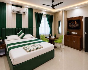 A hotel room with a bed, a desk, a chair, an air conditioning unit, a ceiling fan, and a wall-mounted TV. - The Royal Green Residency (Varanasi)