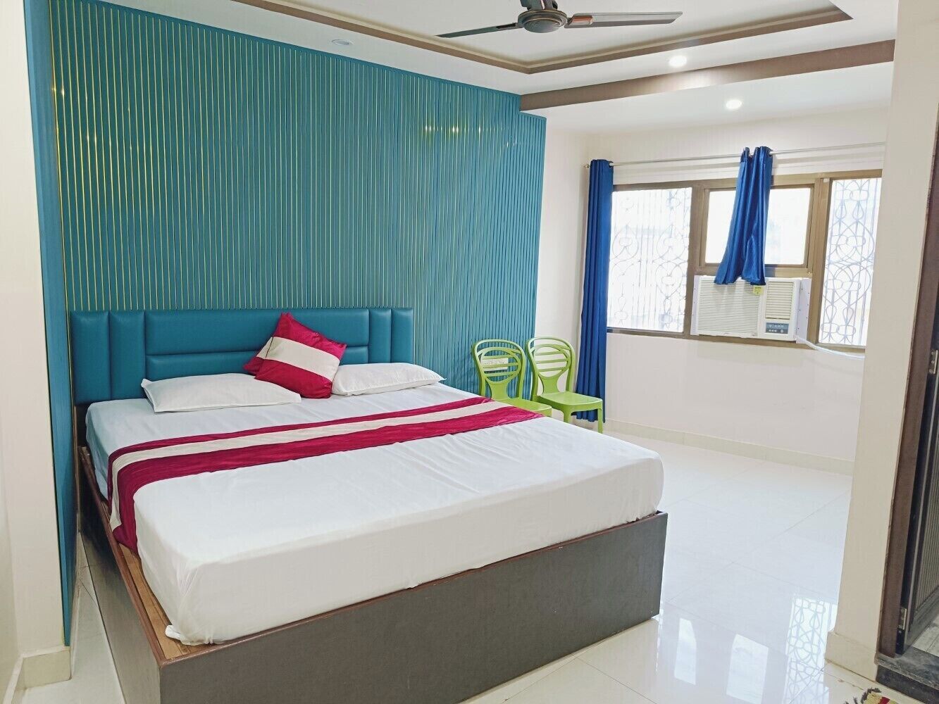 Quarto com cama, ventilador de teto e janela com cortinas.
