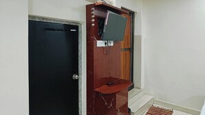 Een kamer met een zwarte deur, een houten plank met een televisie en een klein houten tafeltje.