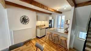Eine moderne Küche mit Holzbalken, einem weißen Heizkörper, einer Uhr und einer Bar mit Barhocker.