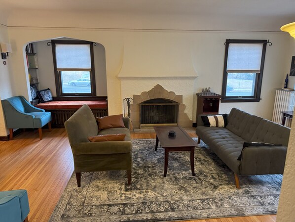 A living room with a fireplace, a blue armchair, a grey sofa, and a patterned rug.