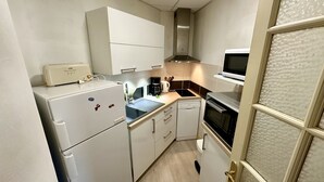 A compact kitchen with a refrigerator, microwave, coffee maker, and a dishwasher. - Le Métropole 410 La Bourboule (La Bourboule)