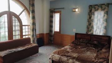 A bedroom with a bed, a bench, a window, and a wall-mounted light.