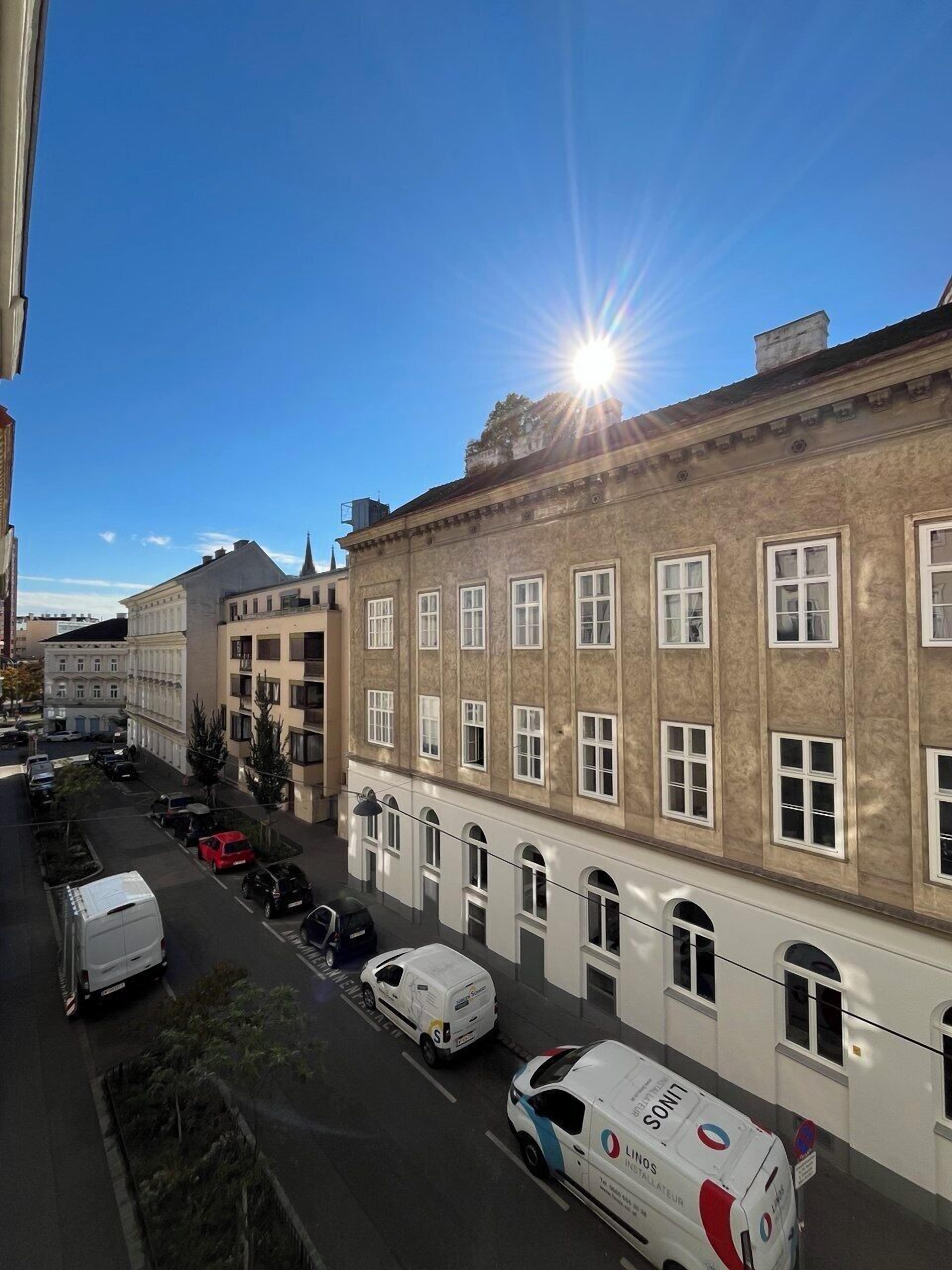 A street view with a building featuring a row of windows and a clear sky.