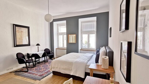 Une chambre à coucher moderne avec un lit, un bureau et une chaise. On y trouve des fenêtres, un tapis et une lampe.