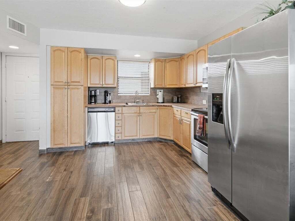 A modern kitchen with wooden cabinets, a stainless steel refrigerator, and a dishwasher.