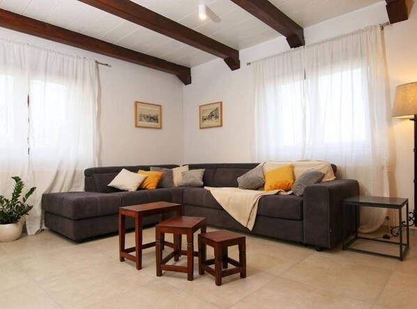 A living room with a dark-colored sofa, two wooden side tables, and a floor lamp. - Secluded Oasis With Pool, Outdoor Kitchen, & Landscaped Terraces (Supetar)