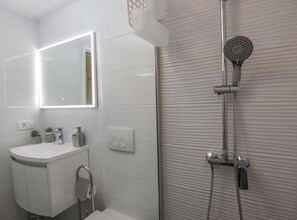A modern bathroom with a white sink, mirror, and shower. - Secluded Oasis With Pool, Outdoor Kitchen, & Landscaped Terraces (Supetar)