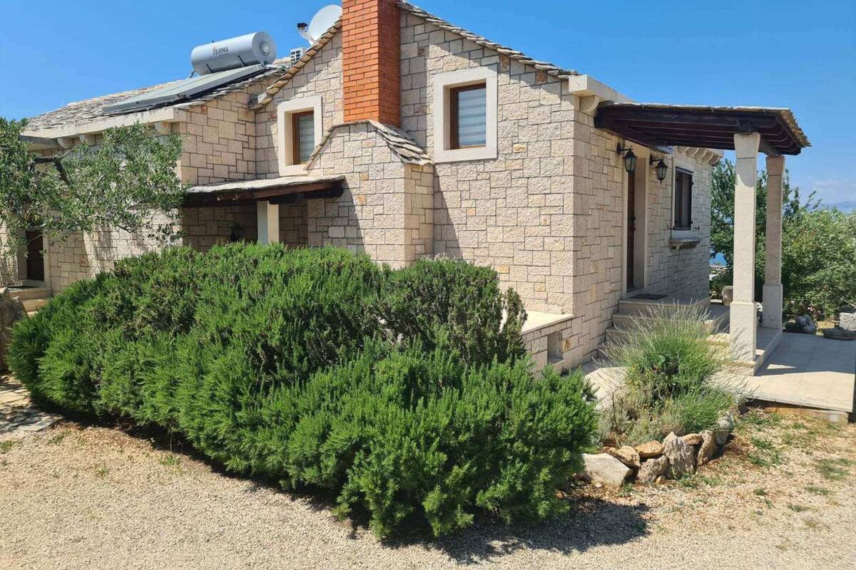 A stone house with a chimney, a satellite dish, and a covered porch.