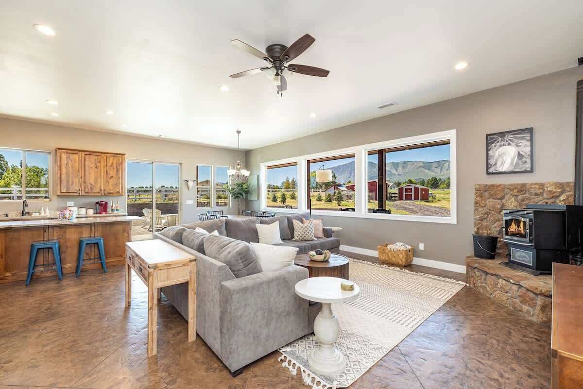 A spacious living area with a gray sofa, a dining table, and a kitchen area with stools.