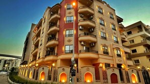 A multi-story building with balconies, arched windows, and a street view. - Settle Inn Janoub Apartments (New Cairo)