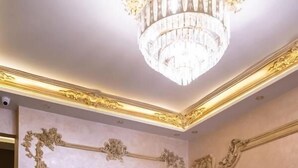 A room with two blue armchairs, a wooden coffee table, a chandelier, and ornate wall decorations. - Settle Inn Janoub Apartments (New Cairo)