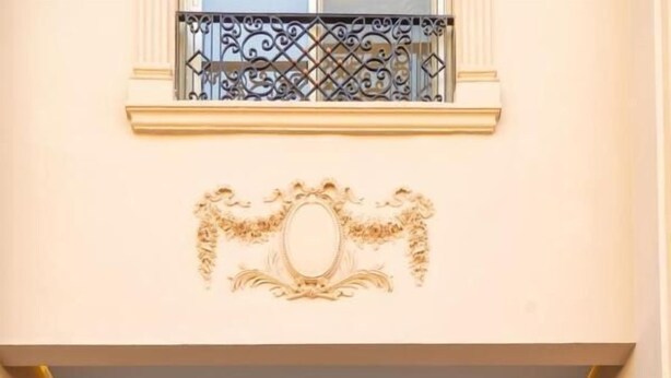 A grand entrance with a staircase, ornate wall decorations, and a large door. - Settle Inn Janoub Apartments (New Cairo)