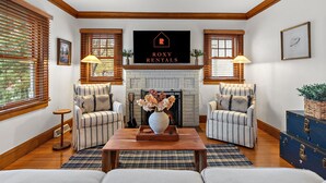 A living room with a fireplace, two armchairs, a sofa, and a coffee table. - "The Darling" at Drew by Roxy Rentals (Minneapolis)