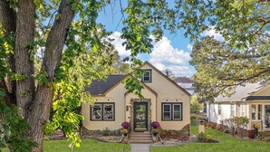 A single-story house with a front porch, a stone foundation, and a well-maintained lawn. - "The Darling" at Drew by Roxy Rentals (Minneapolis)