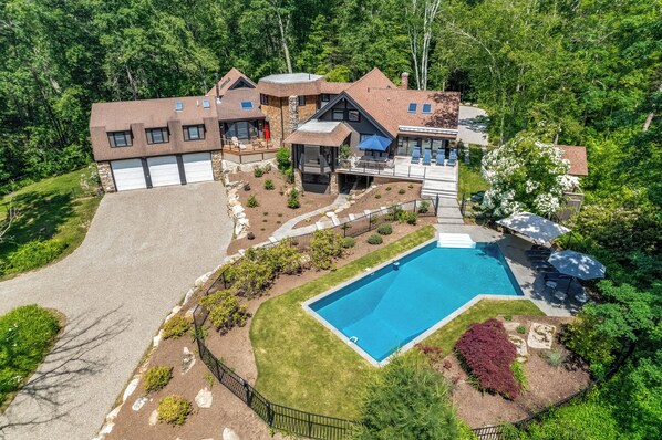 A large, modern house with a swimming pool, multiple garages, and a well-maintained garden.