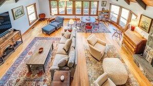 A spacious loft-style living area with high ceilings, large windows, and a mix of seating options including sofas and chairs.