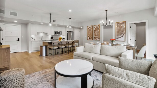 Un salon moderne comprenant un canapé, une table basse et un coin repas avec des chaises.