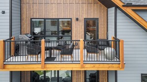 Un immeuble de deux étages doté d’un balcon aménagé avec des sièges d’extérieur et un barbecue.