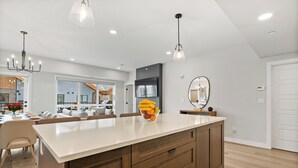 Une cuisine moderne dotée d’un grand îlot central, de meubles en bois et de luminaires suspendus.