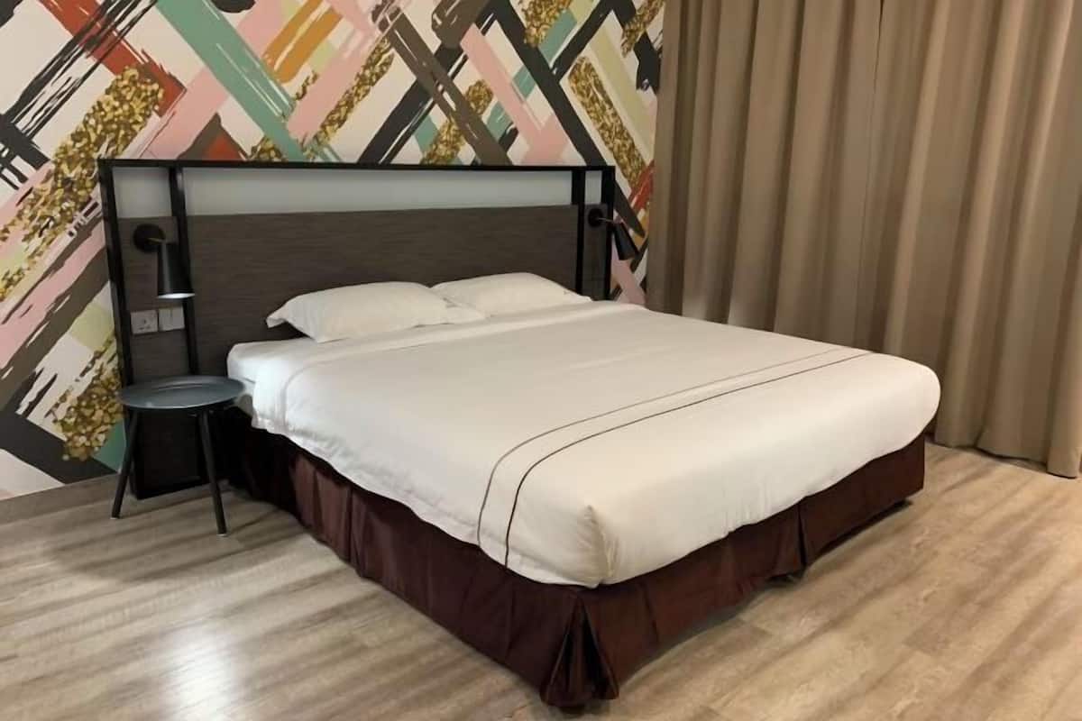 A bed with a wooden headboard, a bedside table, and a wall with a geometric pattern.