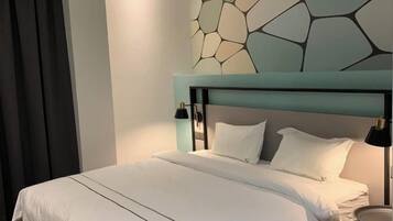 Un lit bien fait, avec du linge de lit blanc, une tête de lit moderne et une œuvre d’art accrochée au mur au-dessus.