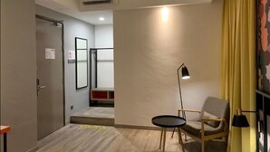 Una habitación moderna con sofá, una mesita, una lámpara y una puerta que da a otra zona.