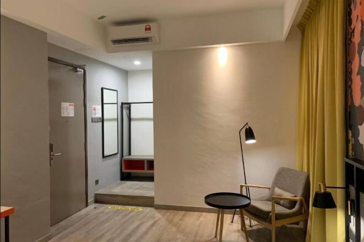 A modern room with a sofa, a small table, a lamp, and a door leading to another area.