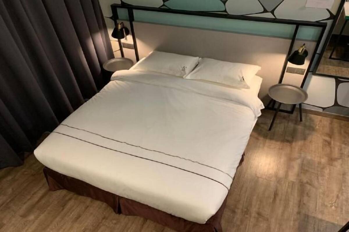 A bed with a headboard, a bedside table, and a small round table.