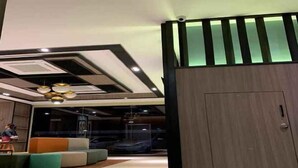 Un interior moderno con una zona de estar, una puerta grande de madera e iluminación empotrada en el techo.