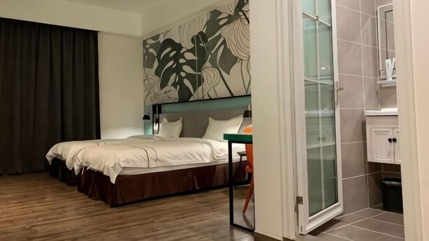 Habitación de hotel con cama, escritorio, baño con ducha y una ventana grande.