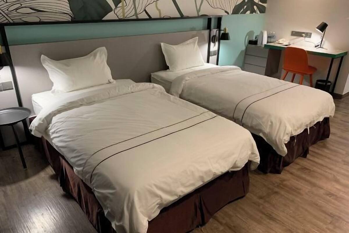 A hotel room with two beds, a desk, and a chair.