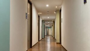 Un largo y estrecho pasillo con suelo de madera y paredes blancas.