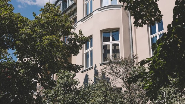 En byggnad med flera våningar, stora fönster och en böjd fasad.