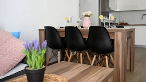 A modern kitchen with white cabinets, a wooden dining table, and black chairs. - Stylish Okrug Gornji Apartment With Terrace and Patio (Okrug)