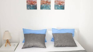 A bedroom with a bed, two pillows, a bedside lamp, and three abstract paintings on the wall. - Stylish Okrug Gornji Apartment With Terrace and Patio (Okrug)