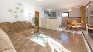 Una sala de estar moderna con un sofá, una mesa de centro de vidrio y una zona de comedor con sillas y una mesa de madera.
