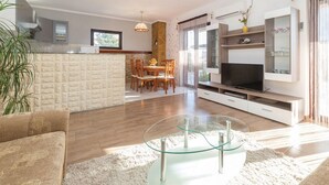 Una sala de estar moderna con una mesa de centro de vidrio, un televisor y un comedor con sillas de madera.