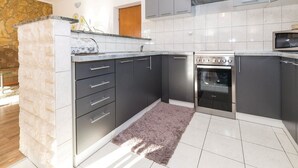 Una cocina moderna con armarios grises, horno empotrado y una pared de acento de piedra.