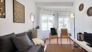 Una sala de estar moderna con un sofá gris, una silla, un televisor y obras de arte en las paredes.